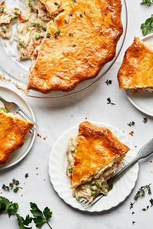 a homemade turkey pot pie filled with turkey, celery, carrot, onion & peas with a slices cut out sitting on plates