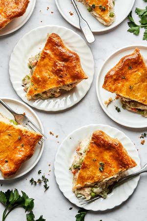 slices of homemade turkey pot pie on plates on the counter made with turkey, vegetables, thyme, salt, pepper and celery seed