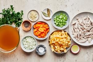 butter, onion, celery, carrots, garlic chicken stock, bay leaves, turkey, noodles, parsley, salt and pepper in bowls