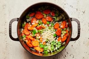 onion, celery, carrots and garlic being cooked in butter in a soup pot for turkey soup