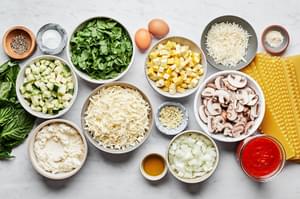 salt, lasagna noodles, vegetables, parmesan, ricotta eggs and spices in bowls to make vegetable lasagna