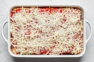 vegetable lasagna in a casserole dish made with layers of mozzarella, vegetables, lasagna sauce, lasagna noodles and marinara