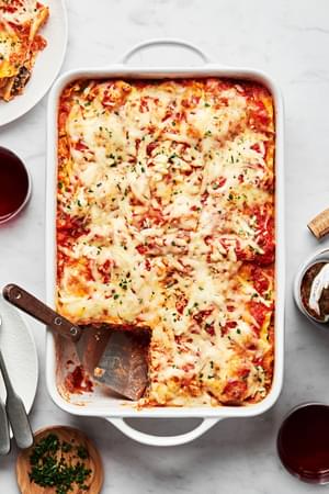 a homemade vegetable lasagna in a casserole dish with a slice taken out