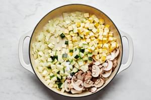onions, garlic, mushrooms, zucchini and squash being cooked in olive oil and salt in a pan for vegetable lasagna