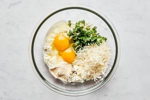 basil, ricotta, Parmesan, eggs, garlic powder, and pepper being mixed together in a glass bowl