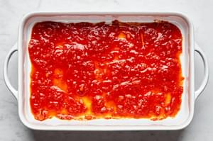 marinara sauce spread on the bottom oaf a casserole dish