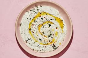 whipped feta dip in a serving bowl made with feta, greek yogurt, olive oil, lemon juices, milk, garlic cloves and spices