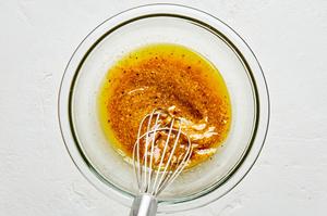 olive oil, red wine vinegar, garlic, mustard, anchovies, salt and pepper being whisked together in a mixing bowl