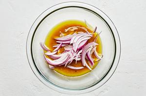 olive oil, red wine vinegar, garlic, mustard, anchovies, red onion, salt and pepper in a mixing bowl for anchovy vinaigrette