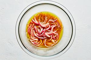 olive oil, red wine vinegar, garlic, mustard, anchovies, red onion, salt and pepper in a mixing bowl for anchovy vinaigrette
