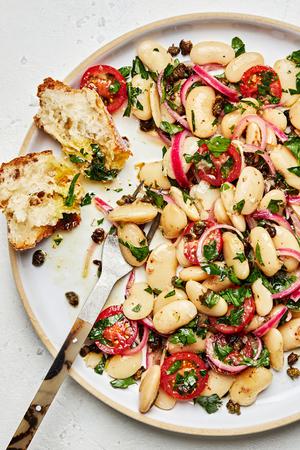 homemade white bean salad with anchovy vinaigrette on a plate with a fork served with crusty bread