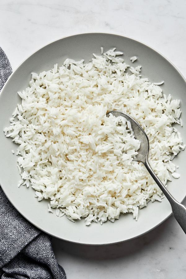 homemade fluffy white rice in a serving bowl with a spoon