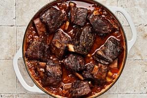 short ribs cooking with onion, celery, carrots, garlic, tomato paste, red wine, beef broth, bay leaf and thyme