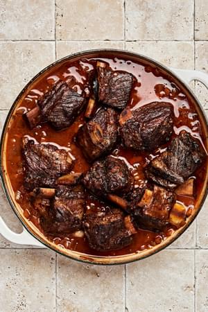 short ribs cooking with onion, celery, carrots, garlic, tomato paste, red wine, beef broth, bay leaf and thyme