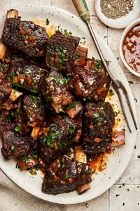 wine braised short ribs on a serving plate made with red wine, spices, celery, onion, carrots and garlic cloves
