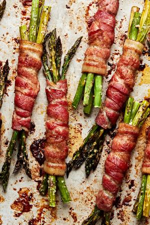asparagus bundles wrapped in bacon on a sheet pan