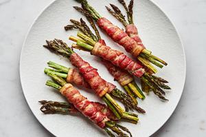 8 bundles of bacon wrapped asparagus on a serving plate