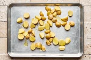 quartered baby potatoes tossed with olive oil and salt on a baking sheet