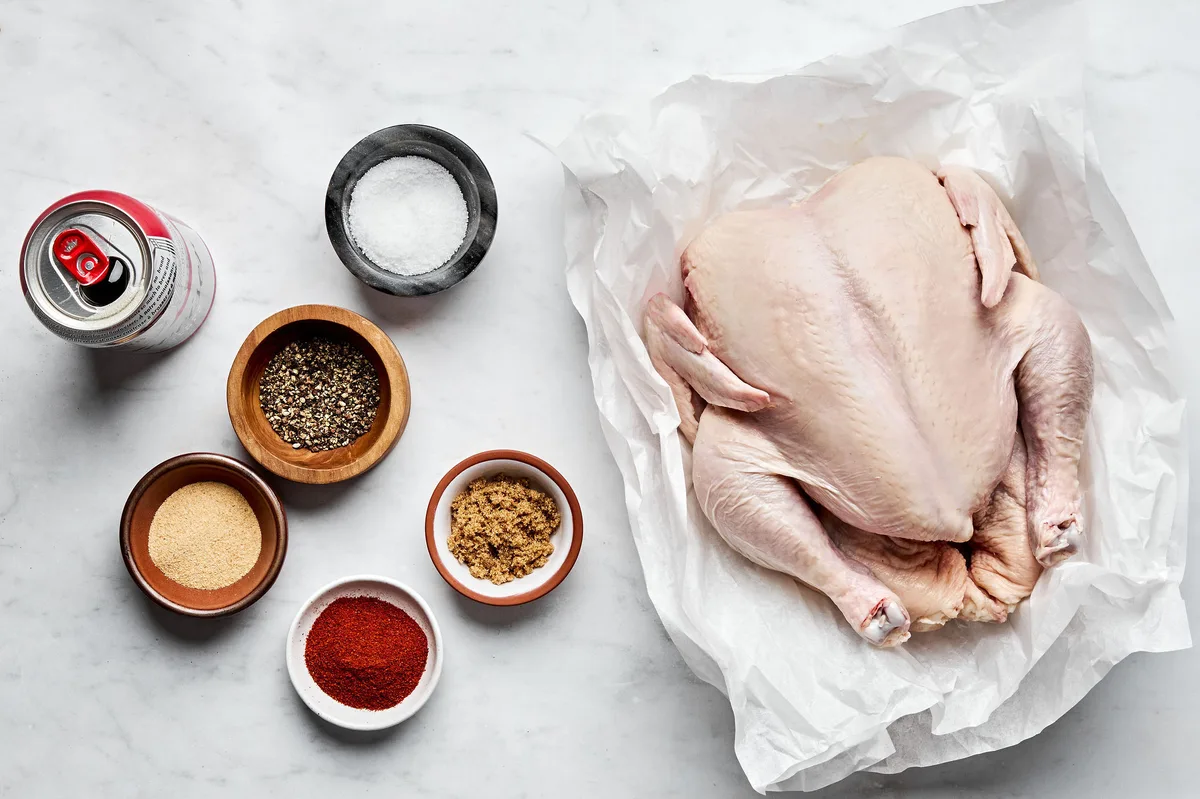 a whole chicken, a can of beer, salt, sugar, paprika, pepper, and garlic powder laid out to make beer can chicken