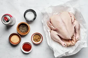 a whole chicken, a can of beer,  salt, sugar, paprika, pepper, and garlic powder laid out to make beer can chicken