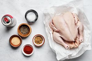 a whole chicken, a can of beer, salt, sugar, paprika, pepper, and garlic powder laid out to make beer can chicken
