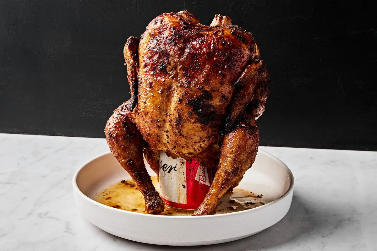 Homemade juicy, cooked beer can chicken resting upright on a serving platter, golden brown and ready to carve.