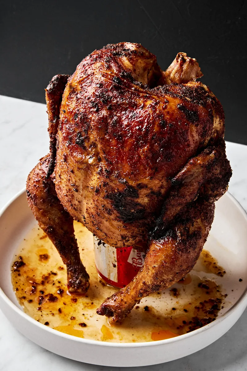 Homemade juicy, cooked beer can chicken resting upright on a serving platter, golden brown and ready to carve.