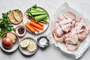chicken parts, onion, carrot, celery, garlic, herbs and spices in prep bowls to make homemade chicken stock