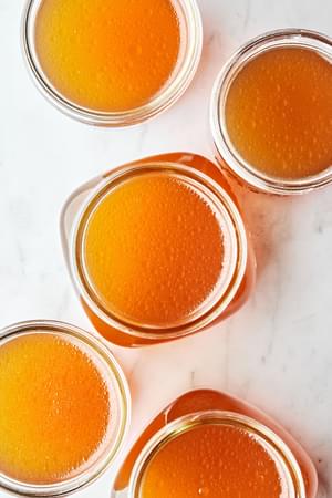 mason jars full of homemade chicken stock made with chicken parts, onion, carrot, celery, garlic, herbs and spices