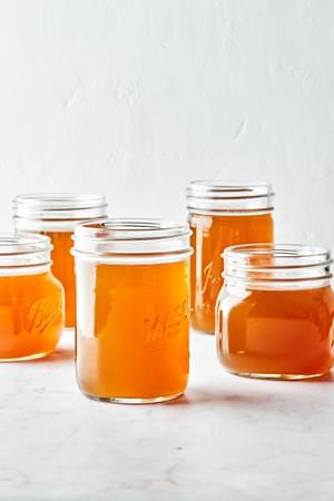 mason jars full of homemade chicken stock made with chicken parts, onion, carrot, celery, garlic, herbs and spices