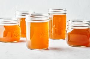 mason jars full of homemade chicken stock made with chicken parts, onion, carrot, celery, garlic, herbs and spices