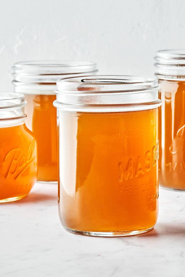 mason jars filled with homemade chicken stock made with chicken parts, onion, carrot, celery, garlic, herbs and spices