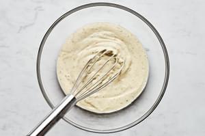 condensed soup, milk, sour cream, bouillon, garlic powder, onion powder, and oregano being whisked together in a glass bowl