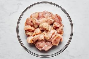 raw chicken seasoned with salt, pepper, garlic powder, onion powder and oregano in a glass bowl