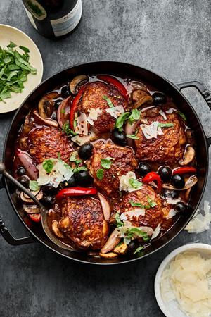 chicken cacciatore in a dutch oven made with breaded chicken thighs, bell pepper, mushrooms, tomatoes, olives and red wine