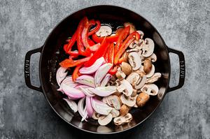 bell pepper, shallots, mushrooms and garlic being cooked in a dutch oven