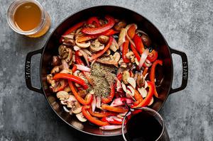 red wine, chicken stock and Italian seasoning being added to a dutch oven with bell pepper, shallots, mushrooms and garlic
