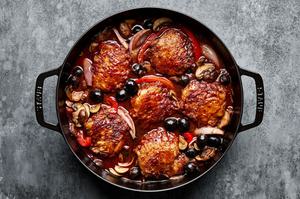 chicken cacciatore in a dutch oven made with peppers, shallots, mushrooms, red wine, crushed tomatoes and olives