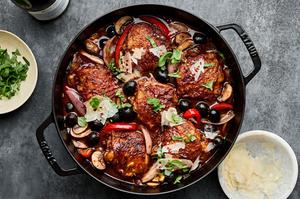 chicken cacciatore in a dutch oven topped with fresh basil, red pepper flakes and Parmesan
