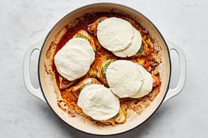 pan cooked marinated chicken topped with pesto and fresh mozzarella slices cooking in a skillet