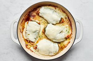 marinated chicken topped with pesto and fresh mozzarella slices cooking in a skillet
