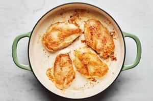 4 chicken cutlets that have been dredged in flour being cooked in a skillet