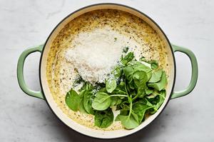butter, garlic, white wine, heavy cream, chicken stock, bouillon, spices, parmesan and spinach cooking in a skillet
