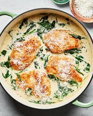 chicken florentine with cooked spinach in a rich white wine cream sauce in a skillet