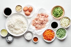 rice, chicken, carrots, peas, onions, eggs, green onions, corn starch, soy sauce, sesame oil and vegetable oil in prep bowls