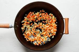 carrots and onions being cooked in a wok in vegetable oil and sesame oil