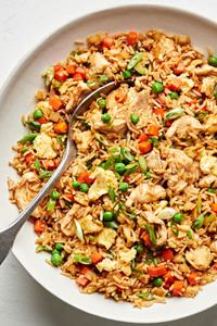 a bowl of chicken fried rice made with carrots, onions, peas, green onions, eggs, soy sauce, coconut aminos and sesame oil
