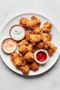 homemade chicken nuggets on a plate served with ranch, fry sauce and ketchup for dipping