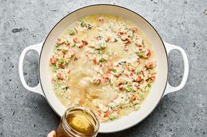 Chicken stock being added to a pot filled with homemade chicken pot pie filling with vegetables and a creamy sauce