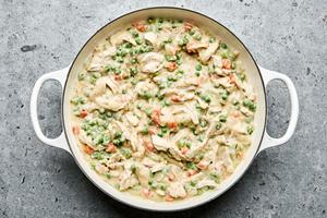 A pot filled with homemade chicken pot pie filling, featuring chicken, vegetables, and creamy sauce simmering together